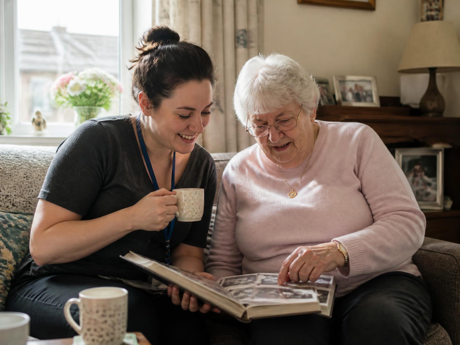 Companion and older woman looking through a photo album together